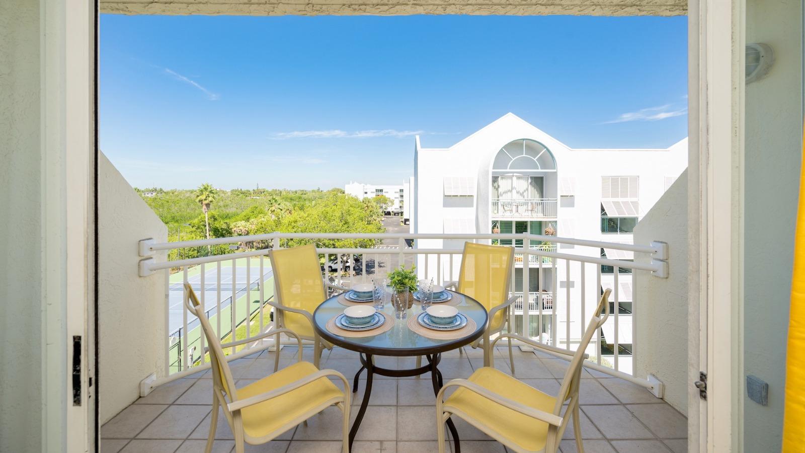 Balcony with a table and chairs overlooking tropical foliage at a Key West vacation rental.